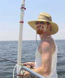 Man with straw had and a cigerette on a boat with a fishing pole