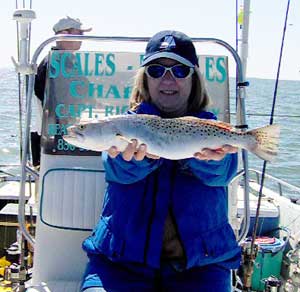 Woman holding up a Seatrout on a boat