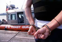 USCG boat in the backgroud of a man handcuffed