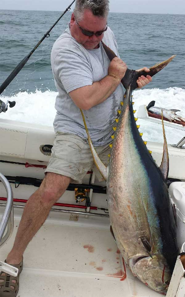 man on a boat holidng up a huge yellowfin tuna