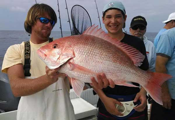 Man on a boat holding a huge pink red snapper