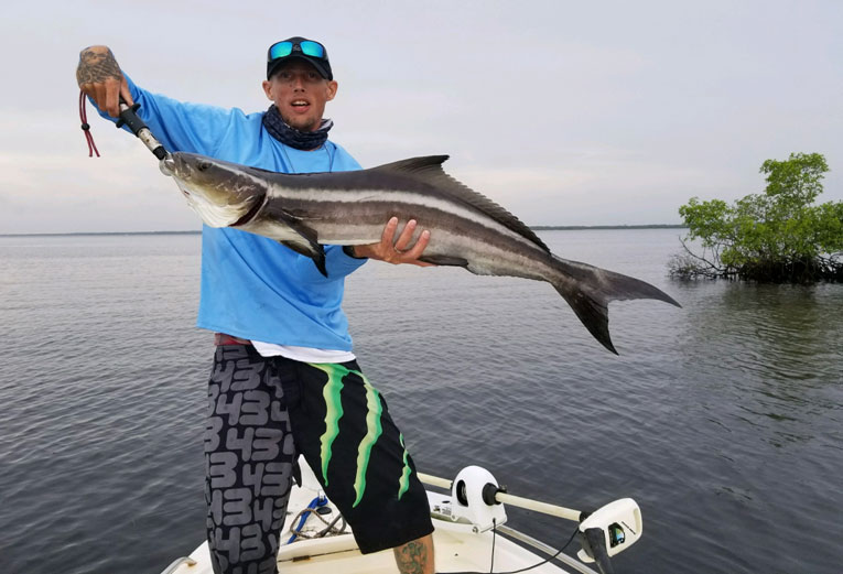 young man on a boat holding a cobia fish