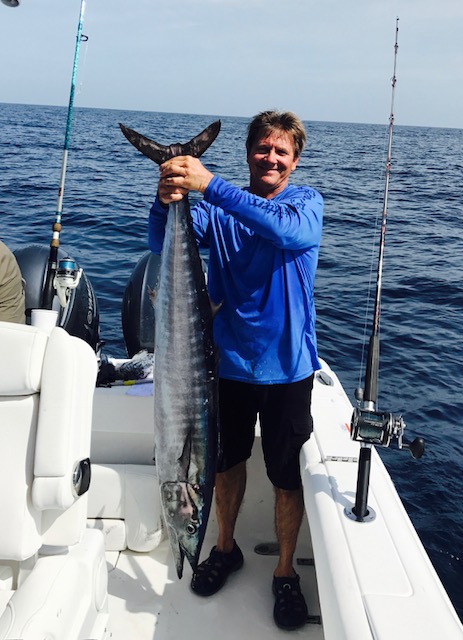 man holding a wahoo fish on a boat