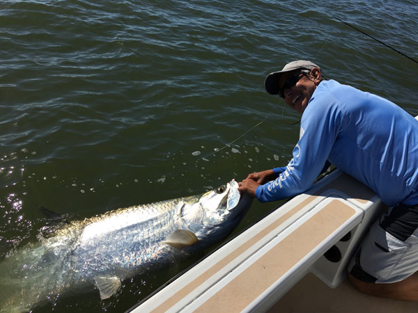 man on a boat holding a huge tarpon