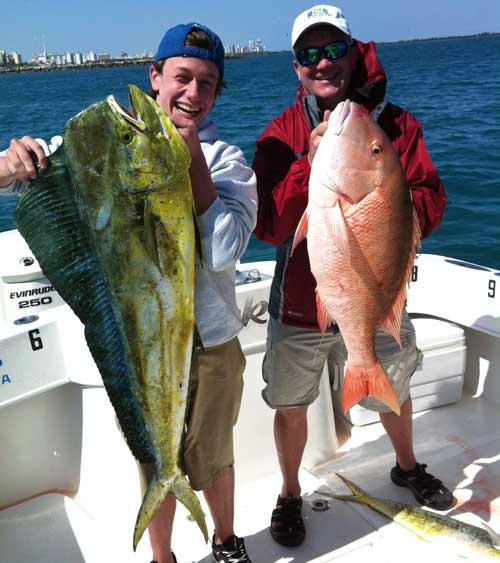 2 men on a boat holding a huge dolphin mahi mahi and a pink mutton snapper
