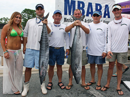 group of men hold a huge kingfish and wahoo with girl in bathing suit