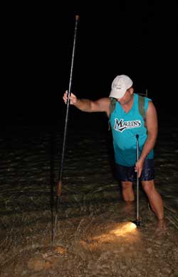 Man gigging on the shore with light and gig