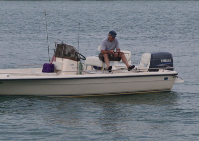 Man looking down into the water fishing from a boat