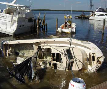 Boats sunk during hurricane wilma, boat in foreground is on its side mostly sunk, another behind it is tipped to the side ready to sink and it's huge