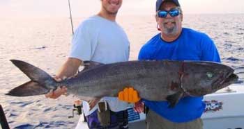 2 men hold a large oilfish on a boat