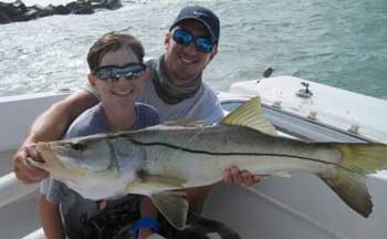 Big Snook held by a man and boy on a boat