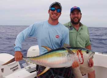 Yellowfin tuna held by 2 men on a boat