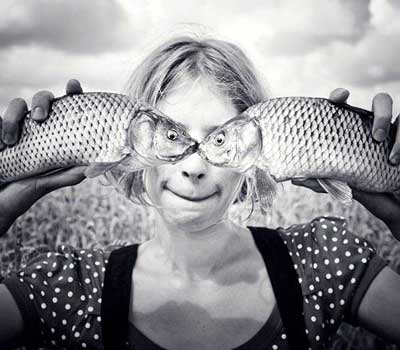 Girl holding two fish to here eyes, looks like they are her eyes