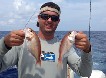 Man holding 2 wenchman snappers on a boat offshore fishing off Texas