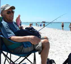 Fisherman on a chair with his pole on Naples beach