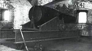 old picture of cannon on a metal wheeled platform infront of a totten shutter