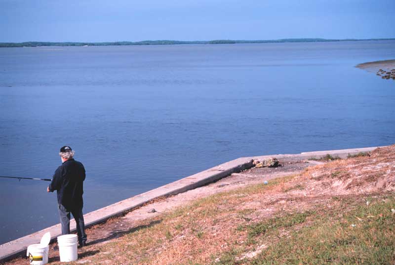 Man standing on sea wall fishing with big water views off Everglades city