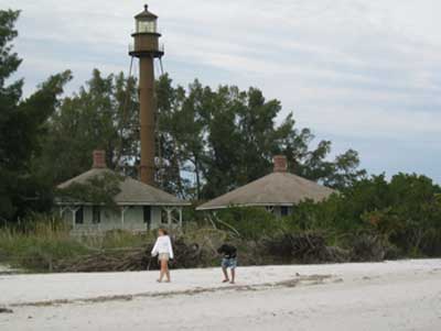 people walking on the beach in front of sanibel lighthouse