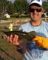 Man with orange gloves on holding a bass