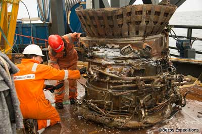 men in orange suits working on the F-1 engine aboard recovery ship at sea