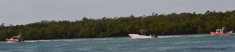 long view of 2 coast guard boats and a sports boat full of men with suits