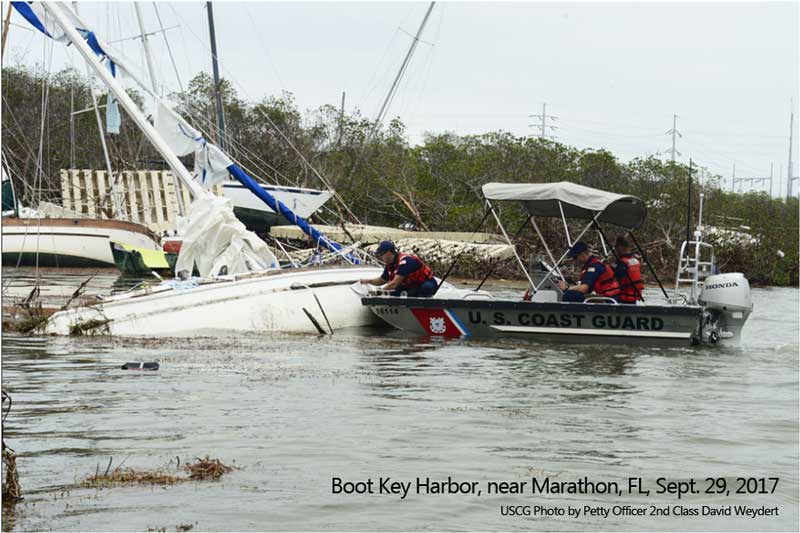 sunken boats in a pile in boot key harbor near marathon after hurricane irma with coast guard boat assessing damages