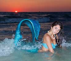 Miss Mermaid August in the water with her tail curved out