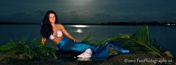 Mermaid at sunset sitting in the weeds at the edge of the water