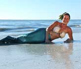 Miss mermaid laying on the beach with scallop shells on chest