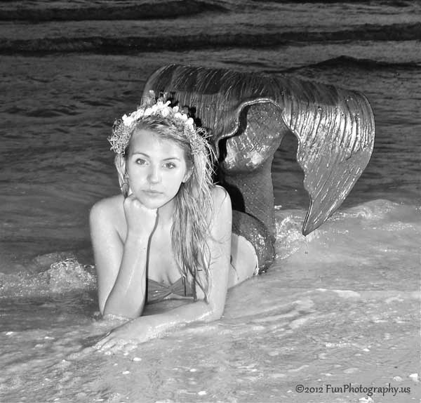 Miss Mermaid of September posing in the surf on a black and white picture