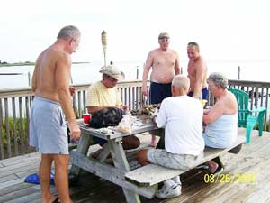 Family cleaning scallops on a wooden picnic table on a dock